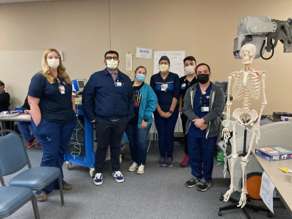 A diverse group of masked figures poses in front of a skeleton, evoking a sense of friendship and intrigue.