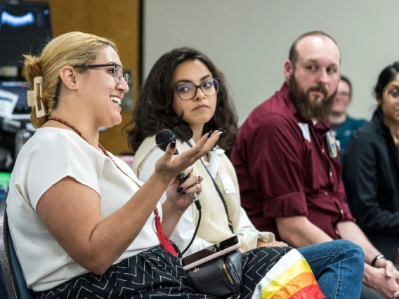 A diverse group of individuals engaged in conversation while seated in chairs, fostering a lively discussion.