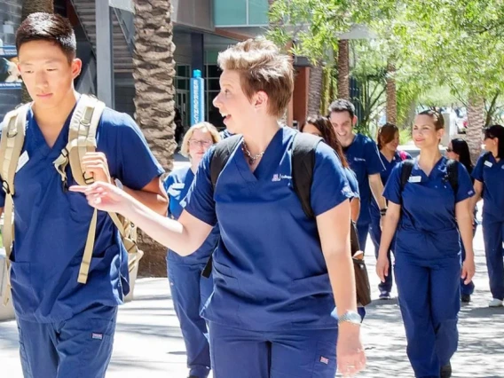 A group of nurses in scrubs walking together along a sidewalk, showcasing teamwork and dedication to healthcare.