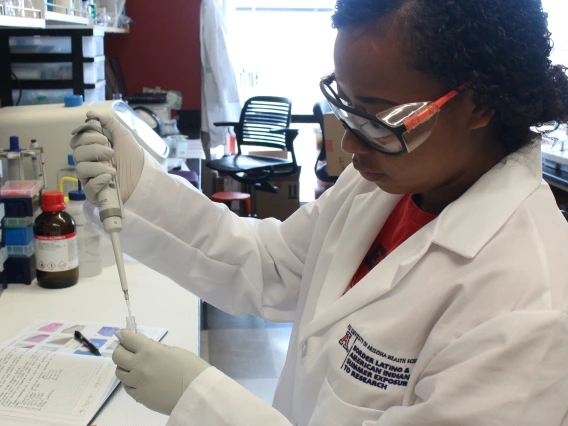 A woman in a lab coat is holding a test tube, showcasing her role in a scientific or laboratory setting.