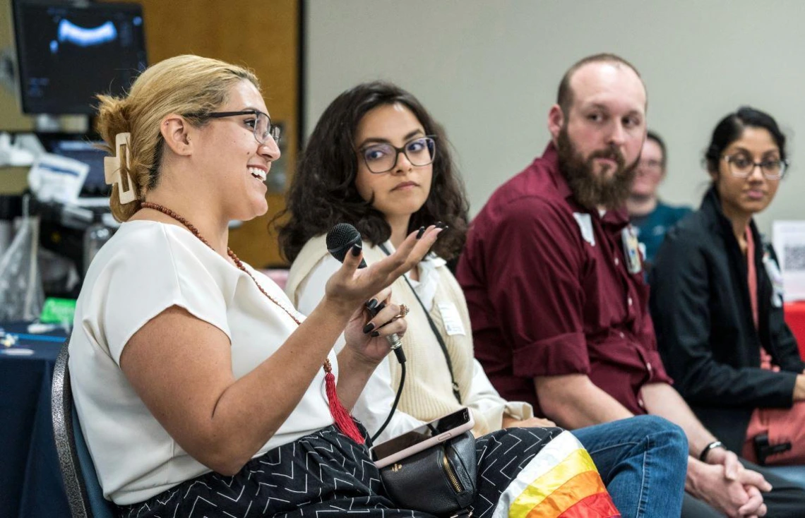 A diverse group of individuals engaged in conversation while seated in chairs, fostering a lively discussion.